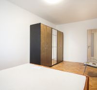 Ložnice s šatníkovou skříní, postelí a podlahou s dřevěným dekorem v 2-pokojovém bytě.