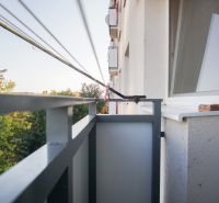 Balkon 2-pokojového bytu v Nových Zámcích s výhledem na zelené stromy.