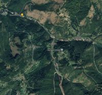 Letecký pohled na Oščadnicu s okolními zalesněnými oblastmi, cestami a stavbami.