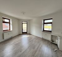 Místnost s okny, bílými stěnami, podlahou s dřevěným dekorem a umyvadlem v kanceláři.