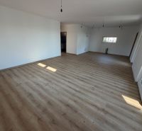 Interiér rodinného domu s bílými stěnami a podlahou s dřevěným dekorem.