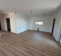 Interiér rodinného domu s podlahou s dřevěným dekorem a minimalistickým osvětlením.