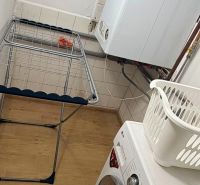 Prádelna v rodinném domě s pračkou, sušákem a podlahou s dřevěným dekorem.