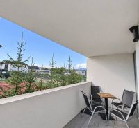 Balkon 2pokojového bytu s posezením, výhledem na zeleň a moderní dlažbou.