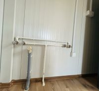 Potrubí a zásuvka v interiérovém prostoru s podlahou s dřevěným dekorem.