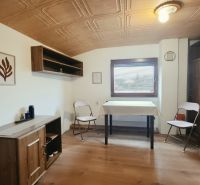 Interiér rekreačního apartmánu s nábytkem s dřevěným dekorem a skládacími židlemi.
