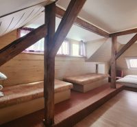 Podkrovní pokoj v rekreačním apartmánu s podlahou s dřevěným dekorem a lůžky.