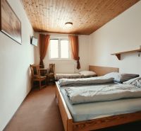 Ložnice v rekreačním apartmánu se dvěma postelemi a TV, podlaha s dřevěným dekorem.
