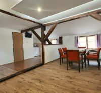 Jídelna s dřevěnými trámy a podlahou s dřevěným dekorem v Rekreačním apartmánu.