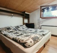Podkrovní ložnice s manželskou postelí, policí a oknem, Rekreační apartmán.