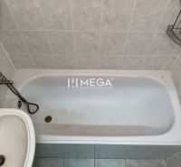 Koupelna s vanou a umyvadlem v 2-pokojovém bytě, obložená světlou dlažbou.