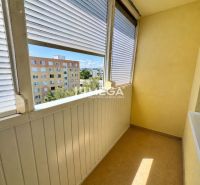 Zasklený balkon s výhledem na paneláky, součást 1-pokojového bytu.