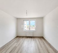 Světlý prázdný prostor s bílými stěnami a podlahou s dřevěným dekorem v 2-pokojovém bytě.