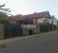 Rodinný dům na Kudlovské ulici v Humenném s kamenným plotem a červenou střechou.