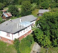 Rodinný dům ve Vyšných Ladičkovcích obklopený zelení, s dvorem a dřevěnou přístavbou.