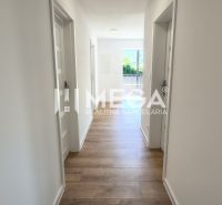 Chodba ve 4-pokojovém bytě, podlaha s dřevěným dekorem, světlé stěny, vstup na balkon.