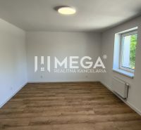 Pokoj ve 4pokojovém bytě s bílými stěnami a podlahou s dřevěným dekorem.