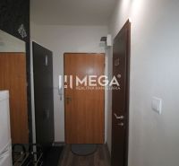 Chodba v rekreačním apartmánu s podlahou s dřevěným dekorem, tapety a lednice.