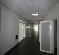 Kanceláře s bílými stěnami, tmavou podlahou a prosvětlenými skleněnými dveřmi.