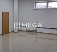 Kanceláře s bílými stěnami a oknem, podlaha s dřevěným dekorem, stůl v rohu.