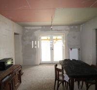 Nedokončený interiér s kuchyňským stolem, židlemi a skříní v rodinném domě.