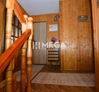 Interiér rodinného domu se schodištěm, dřevěným obkladem a podlahou s dřevěným dekorem.