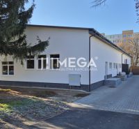 Budova obchodních prostor na Tyršově ulici v Humenném obklopená stromy.