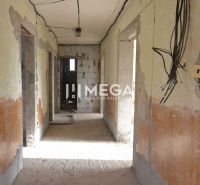 Interiér rozestavěného rodinného domu s odhalenou elektroinstalací a neomítnutými stěnami.