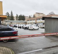 Parkoviště před kancelářemi na ulici 26. listopadu v Humenném se závorou a auty.