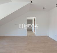 Pokoj v 2-pokojovém bytě s bílými stěnami a podlahou s dřevěným dekorem.