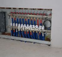 Rozvodná skříň instalací v interiéru rodinného domu s modrými a červenými trubkami.