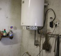 Bojler v technické místnosti rodinného domu se zásobníky na stěně.