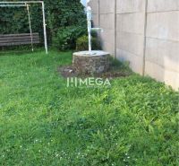 Zahrada s trávníkem a studnou u rodinného domu na Staniční ulici v Belej nad Cirochou.