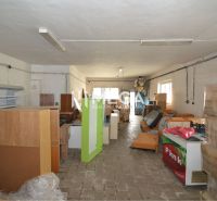 Obchodní prostory s uloženými regály, boxy a zařízením, podlaha s dřevěným dekorem.
