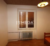 Pokoj ve 3-pokojovém bytě s podlahou s dřevěným dekorem a centrálně umístěným radiátorem.