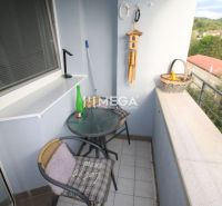 Balkon 2-pokojového bytu s kavárenským stolkem a výhledem na zeleň.