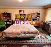 Izba v rodinnom dome s posteľou, kobercami, policami a písacím stolom.