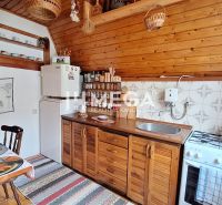 Kuchyně v chatě s podlahou s dřevěným dekorem, dřevěnými skříňkami a jídelním stolem.