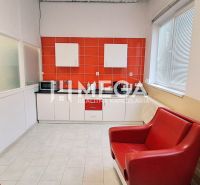 Interiér obchodních prostor s červeným křeslem a oranžovým obkladem stěny.