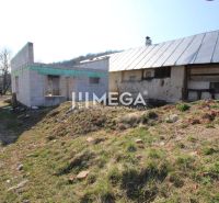 Rozestavěný rodinný dům v Zbojné s okolní zelení a starší budovou.