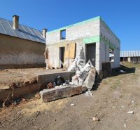 Rodinný dům v Zbojném během výstavby s rozestavěnými zdmi a stavebním materiálem.