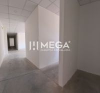 Chodba v kanceláři s bílými stěnami, podlaha z betonu, podhledový strop.
