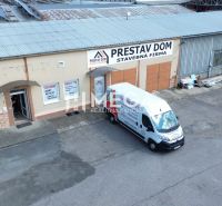 Budova na Fidlikově ulici v Humenném s nápisem „Přestav Dům” a parkovištěm.