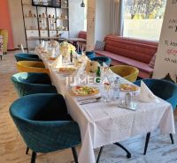 Stylové gastro prostory s dekorativní výzdobou, podlaha s dřevěným dekorem a elegantní židle.