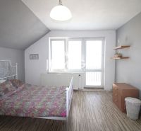 Interiér rodinného domu s postelí, skříní a podlahou s dřevěným dekorem.