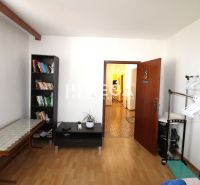 Pokoj ve 4pokojovém bytě s knihovnou a podlahou s dřevěným dekorem.