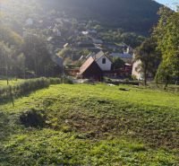 Pozemek na bydlení v Košeckém Podhradí obklopený přírodou a domy, pod vrcholy hor.