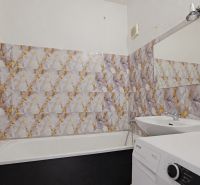 Koupelna s vanou a pračkou v 3-pokojovém bytě, obklady s výrazným vzorem.
