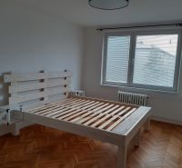 Světlá ložnice s dřevěnou postelí a podlahou s dřevěným dekorem v 2-pokojovém bytě.