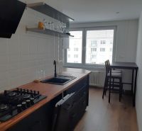 Kuchyně v 2-pokojovém bytě s podlahou s dřevěným dekorem a barovým stolem.